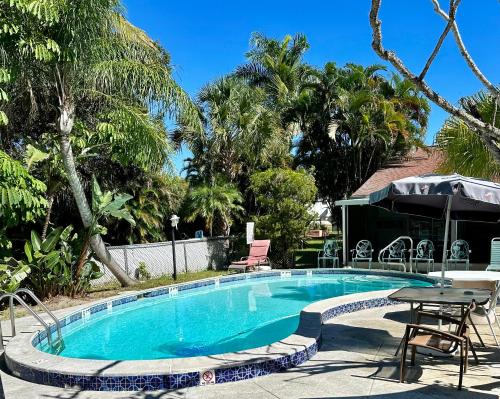una piscina con mesa, sillas y árboles en Conty's Motel, en Naples