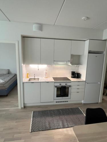 a kitchen with white cabinets and a stove top oven at New built One bedroom Apartment nearby Train station in Vantaa