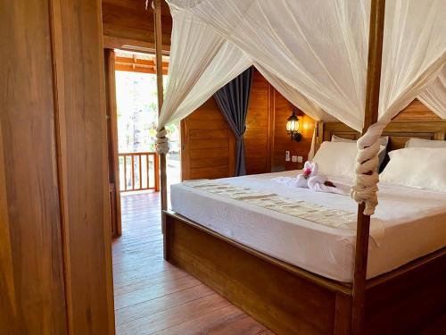 a bedroom with a canopy bed with a teddy bear on it at Ings Garden in Gili Islands