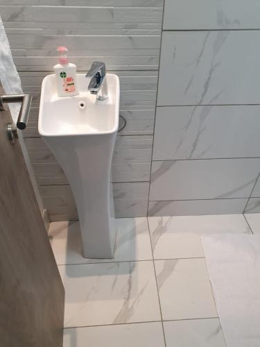Un baño con un lavabo blanco en una habitación. en Intercultural Apartment Nairobi Two Rivers, en Nairobi