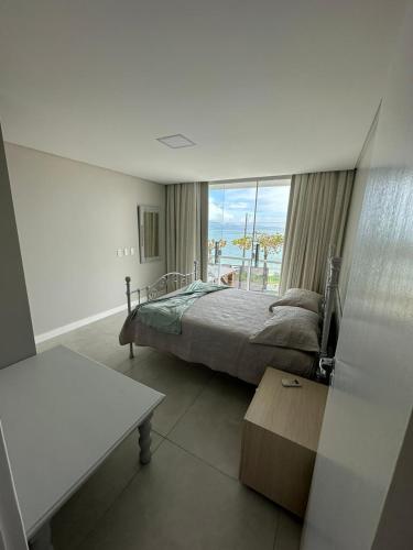a bedroom with a bed and a view of the ocean at Apartamento Frente Mar na Baía de Porto Belo in Porto Belo