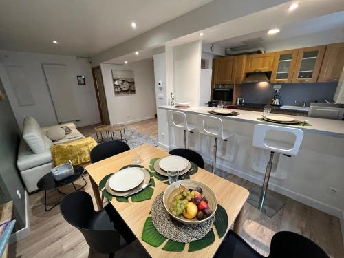 a kitchen and living room with a table with a bowl of fruit at Le Caladois in Villefranche-sur-Saône