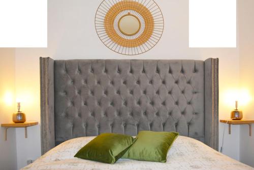 a bed with a gray headboard with a green pillow at Gîte La Capucine in Saint-Avertin