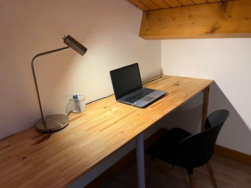 a laptop computer sitting on a wooden desk with a lamp at Le Caladois in Villefranche-sur-Saône