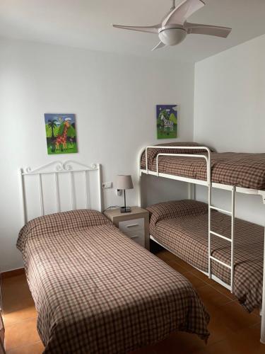 エル・ボスケにあるApartamento Sierra Leónのベッドルーム1室(二段ベッド2台、シーリングファン付)