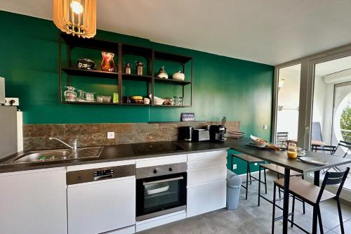 - une cuisine avec des murs verts et une table avec des chaises dans l'établissement L'Emeraude au soleil Studio avec coin nuit dans résidence sur la plage, au Grau-du-Roi