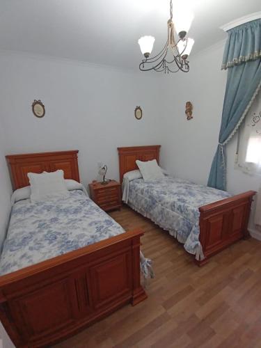 a bedroom with two beds and a chandelier at Casa la Torre in Cambados