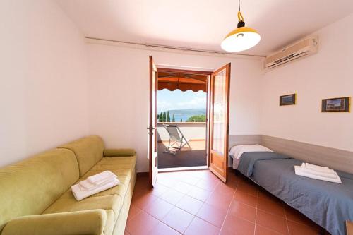 ein Wohnzimmer mit einem Sofa und einem Balkon in der Unterkunft Residence Le Grazie Est in Capoliveri