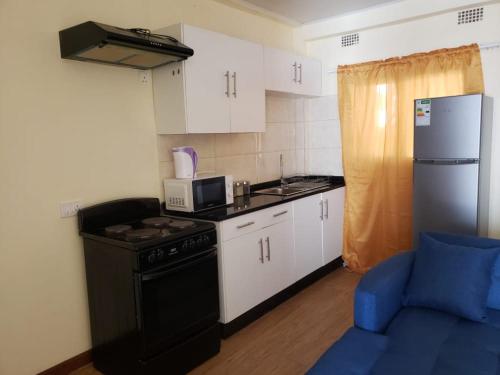 a small kitchen with a stove and a refrigerator at LouieVille One Bedroom Apartment in Lusaka
