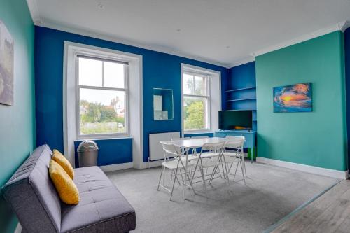 sala de estar con paredes azules, mesa y sillas en One-Bedroom Apartment: Sleeps 4 Comfortably, en Berwick-Upon-Tweed