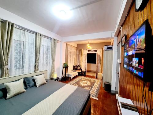 Schlafzimmer mit einem Bett und einem Flachbild-TV in der Unterkunft Peace Valley German Heritage Cottage Home Stay in Darjeeling