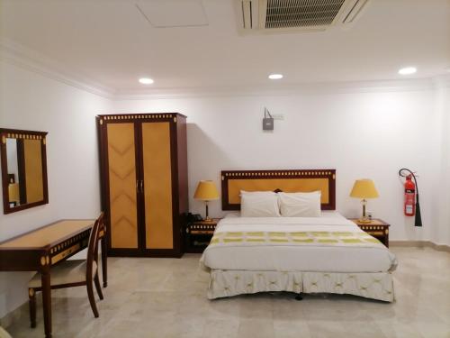 a bedroom with a bed and a table and a desk at Pioneer Hotel Apartments Muscat in Muscat
