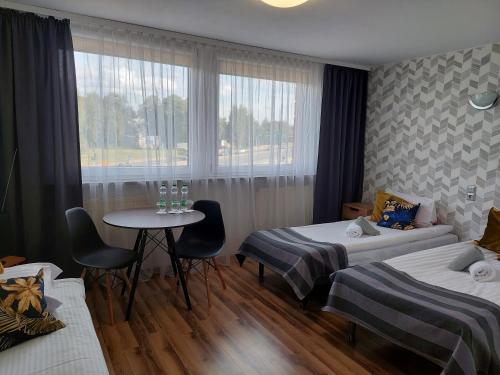 een kamer met 2 bedden, een tafel en een raam bij Noclegi Bytom - OPAL in Bytom