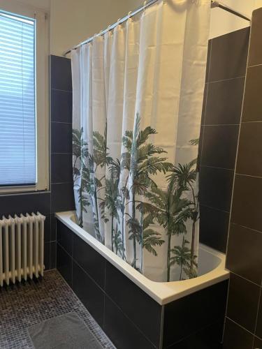 a bathroom with a shower curtain with palm trees at Schängelrooms in Koblenz