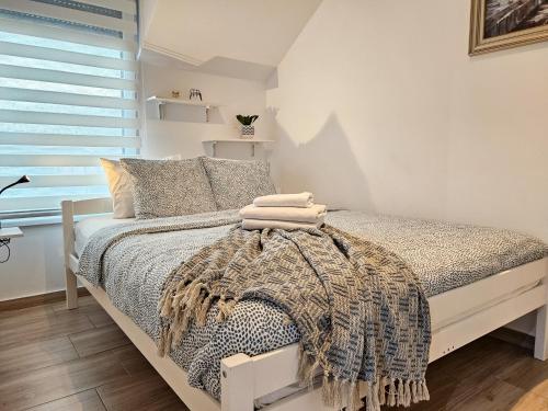 a bedroom with a bed with a blanket on it at Roman Apartman in Sremska Mitrovica