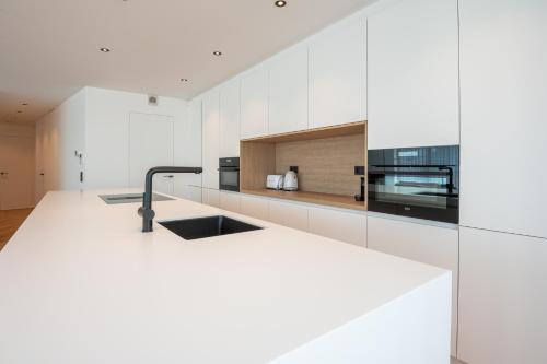 een witte keuken met een wastafel en een magnetron bij Dunvegan in Oostende