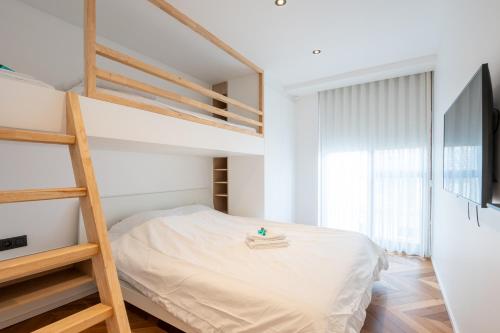 a white bedroom with a bunk bed and a ladder at Dunvegan in Ostend