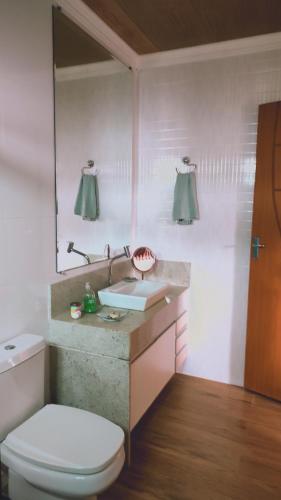 uma casa de banho com um lavatório, um WC e um espelho. em Recanto Duas Rosas em Venda Nova do Imigrante