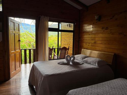 1 dormitorio con 2 camas y zapatillas. en Cabañas el Bosque, en Turrialba