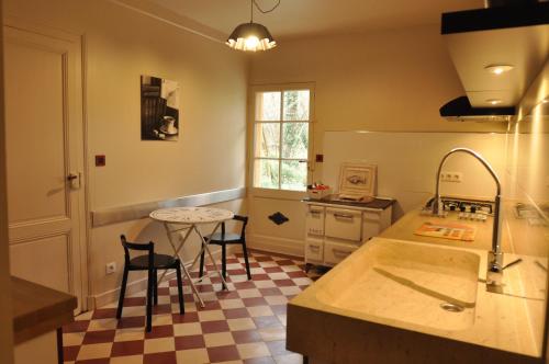 eine Küche mit einer Theke, einem Tisch und Stühlen in der Unterkunft Le Pavillon du Lac in La Brede