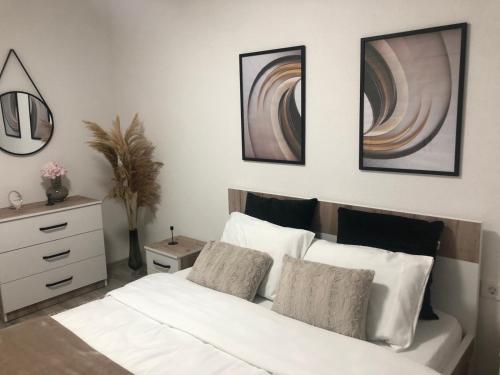 a bedroom with a white bed with three pictures on the wall at Apartment Prizren New and Modern in Prizren