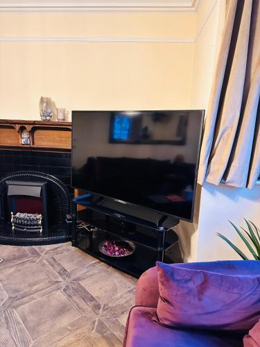 a living room with a large flat screen tv at Hestia Travel Slough in Slough