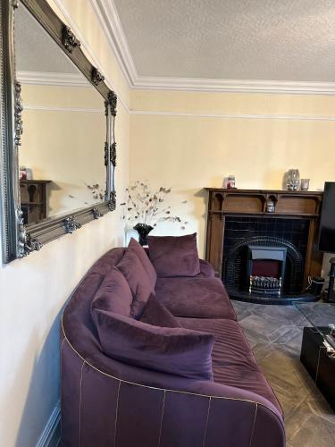 a large couch in a living room with a fireplace at Hestia Travel Slough in Slough