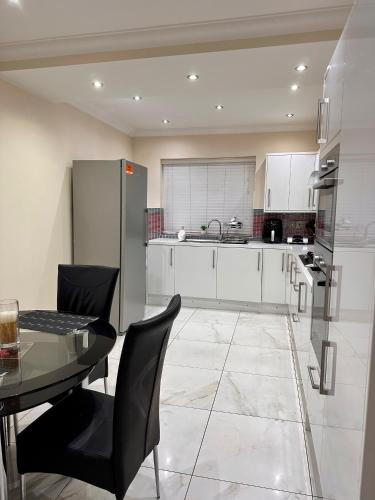 a kitchen with a table and chairs and a refrigerator at Hestia Travel Slough in Slough