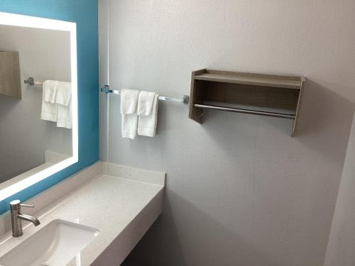 y baño con lavabo, espejo y toallas. en Pleasanton Executive Inn, en Pleasanton