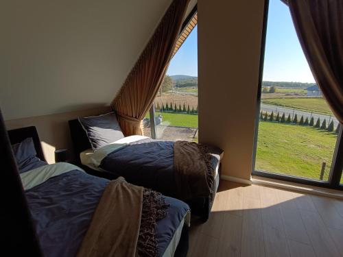 two beds in a room with a large window at Domki Pod Łysicą in Krajno Pierwsze