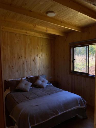 1 dormitorio con 1 cama grande en una pared de madera en Cabaña en Pupuya Navidad, en Navidad