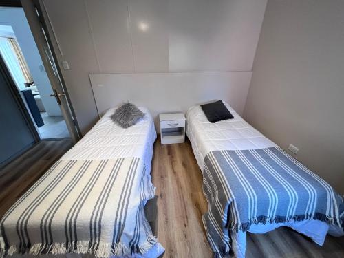 2 Betten in einem kleinen Zimmer mit Holzböden in der Unterkunft Tierra de Canoeros in Ushuaia