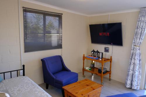 a bedroom with a blue chair and a tv at Blue Sky Retreat in Vredenburg