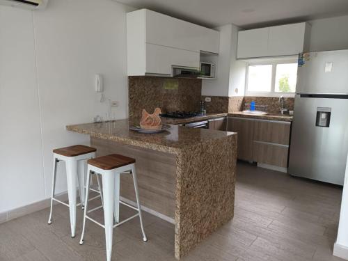 cocina con encimera con taburetes y nevera en Beautiful Beach Apartment in Zazue, en Santa Marta