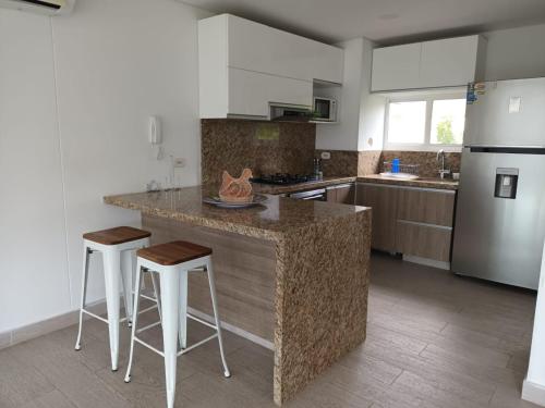 Una cocina con una encimera con taburetes y un refrigerador. en Beautiful Beach Apartment in Zazue, en Santa Marta
