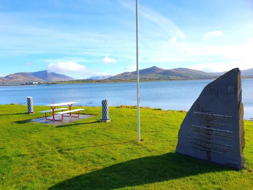 a bench and a sign next to a body of water at Shore Cottage on Valentia Island - Cosy comfort at the sea in Kerry in Valentia Island