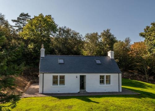a white house in the middle of a yard at Isle of Skye luxury cottage near Portree in Kensaleyre