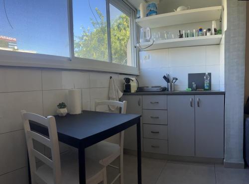 una pequeña cocina con mesa negra y sillas en Cozy Studio Apartment in Haifa, en Haifa