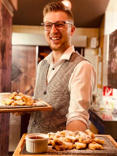 a man in a kitchen holding a tray of food at AlpenParks Montana Apartments in Matrei in Osttirol