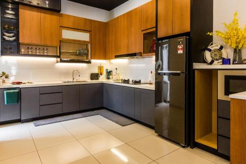 uma cozinha com armários de madeira e um frigorífico preto em Varnen Cozy Haven em Bukit Mertajam