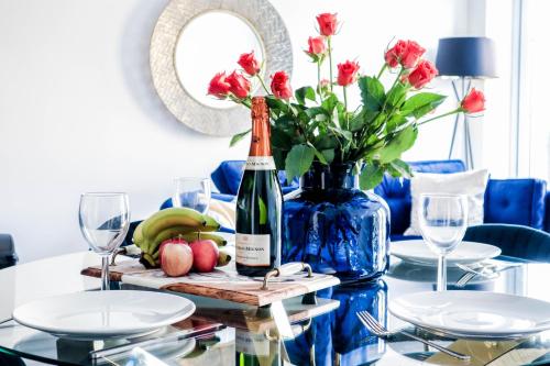 a table with a bottle of wine and a vase of flowers at Elegant Apartments in Staines l Free Onsite Parking in Staines