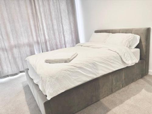 a bed with a gray frame and white sheets and pillows at Ace Apartments in Barking