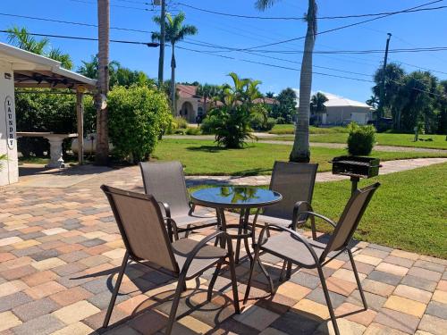 um pátio com uma mesa, cadeiras e comodidades para churrascos em 2 Bed Cottage with Pool, Close to Beach! BBQ Grills & Patio em Fort Myers