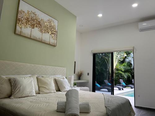 a white bedroom with a large bed and a patio at Célèbre VILLA VENUS Playacar - 24 Pax in Playa del Carmen