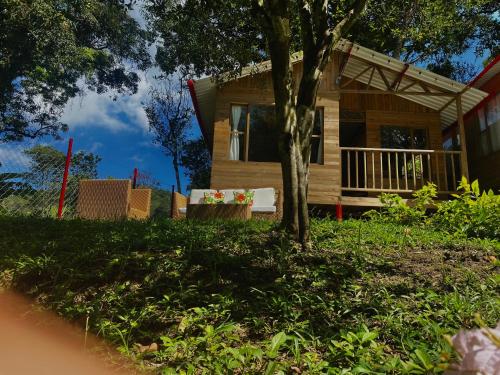 a log cabin with a tree and a house at cabañas la vega in La Vega