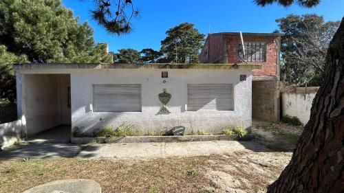een wit huis met twee garagedeuren en bomen bij Il Giardino de Santa in Santa Teresita