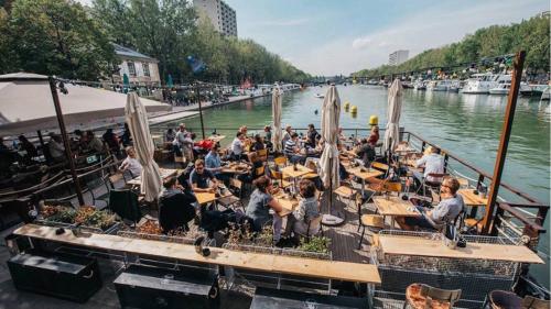 a group of people sitting at tables on a dock at Cosy spacieux appartement balcon - Ourcq Paris 19 in Paris