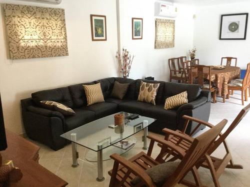 a living room with a black couch and a table at Detached 3 bed Villa, private pool - Nirvana Pool Villa 2 in Nong Prue