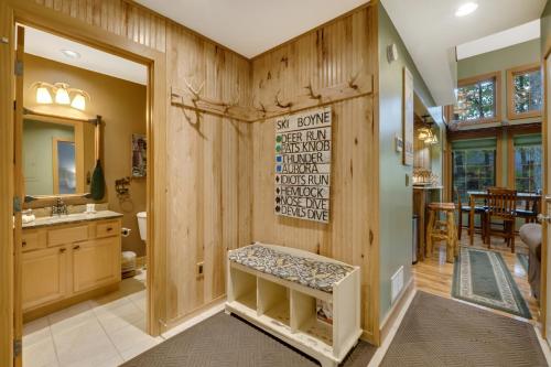 a bathroom with wooden walls and a sink and a mirror at 734 Disciples Village Condo in Boyne Falls