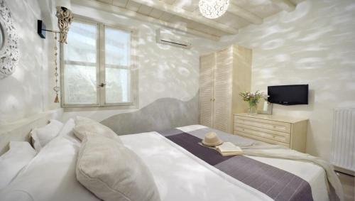 a bedroom with a white bed with a hat on it at Villa Mon Rêve with Private Jacuzzi "5-minute walk - Ornos beach" in Mýkonos City